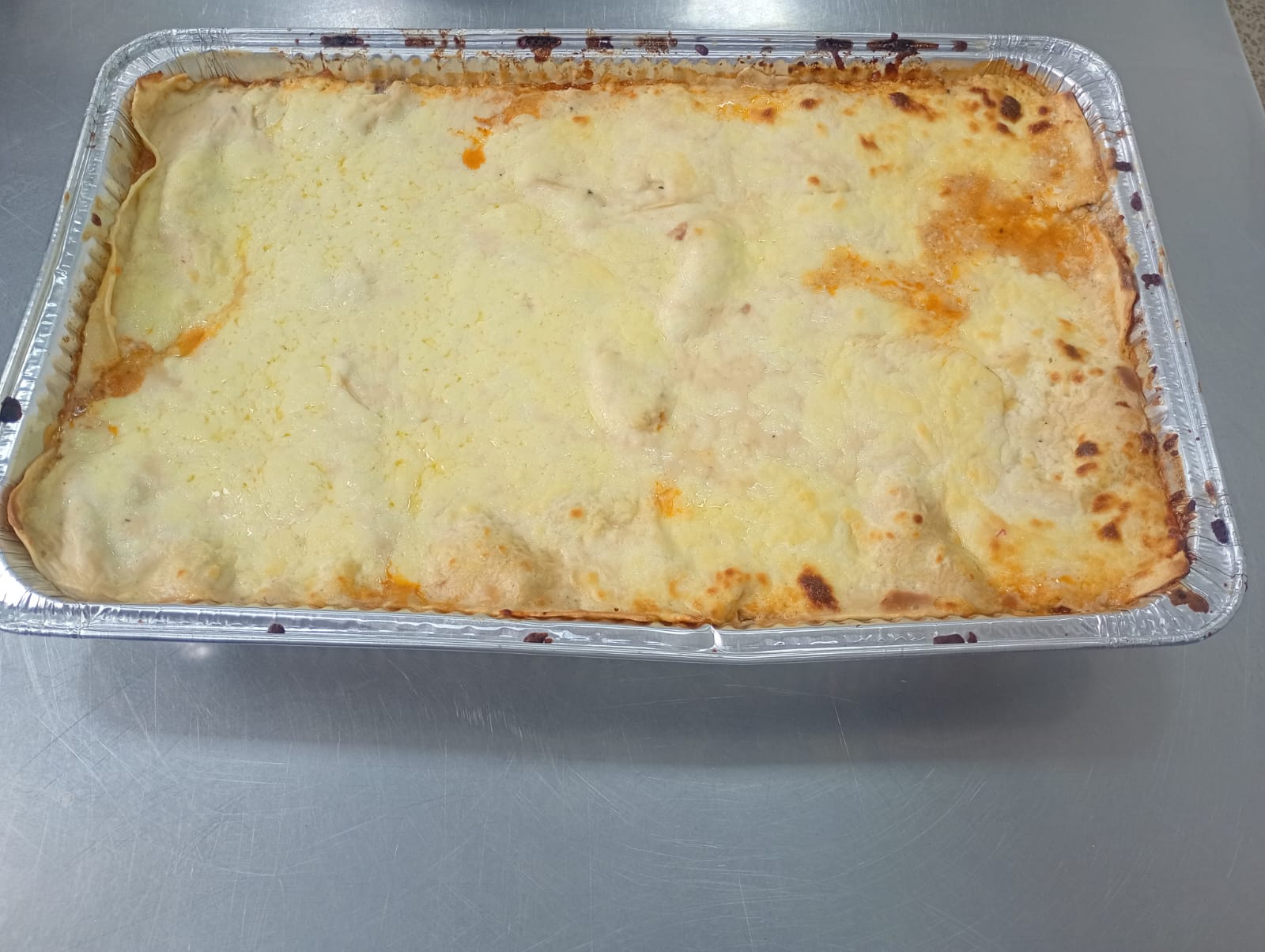 Lasaña recién horneada en bandeja de catering